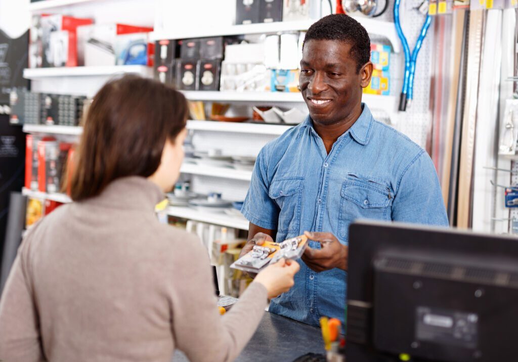 Competent glad diligent seller consulting young smiling woman about purchase of supplies for household works in store